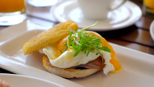 レストランでの朝食テーブルの上に卵ベネディクト ホテルの料理 ハムとおいしいポーチドエッグ サラダ マフィンパンとオランデーズソース リゾート内で朝食を提供 — ストック動画