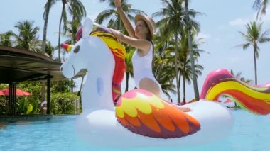 Yaz tatili. Mayo giymiş güzel, sıska bir kadın yüzme havuzunda yüzüyor mavi havuzda yüzüyor, dans ediyor ve Tayland 'da tatilleri kutluyor.