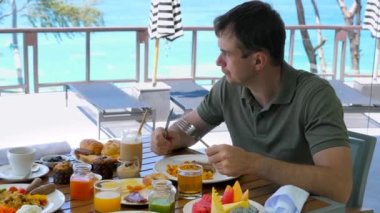 Kızgın adam kahvaltı yapar ya da turkuaz deniz altyapısı olan bir restoranda brunch yapar. Sabahları tatil köyündeki kafede mutsuz bir erkek turist. Saldırgan, sinirli, öfkeli, çılgın insanlar konsepti.