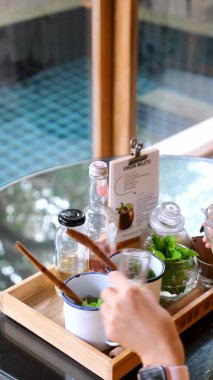 Handmade refreshing mojito cocktail in a glass. A refreshing soft drink. Woman hands pouring a sweet lime juice into a cup with mint and sparkling water with ice. Recipe for a non-alcoholic mojito