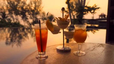 Cocktails for two with snacks assortment on table in outdoor luxury restaurant at tropical hotel at sunset. Exotic fruit cold mocktails with appetizers at evening dusk in resort bar with sea view.