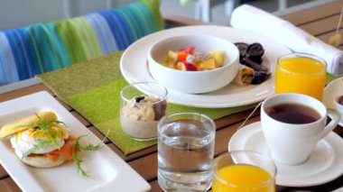 Kahvaltı ile otel masası. Modern tropikal tatil beldesinde yemek servisi yaptım. Taze meyve, meyve suyu, yumurta ve mısır gevreğiyle restoranda iki kişilik yemek. Tatil, tatil, hafta sonu konsepti