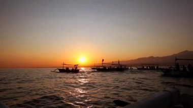 Okyanustaki ahşap bir teknede gün doğumuyla karşılaşmak. Bali 'nin kuzeyinde yunus arayışı içinde. Tur teknesi yolcuları sudaki hayvanları izliyor. Asya tatili, macera, turistik eğlence