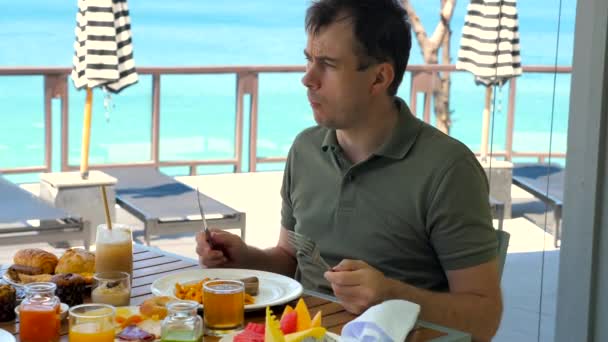 Young Man Eating Brunch Restaurant Tropical Hotel Turquoise Sea Background — Vídeo de Stock