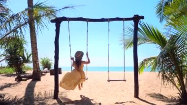 Vacation cheerful woman in dress and straw hat, swinging for joy, relax and leisure. Travel girl enjoys her holidays at luxury resort near sea. 