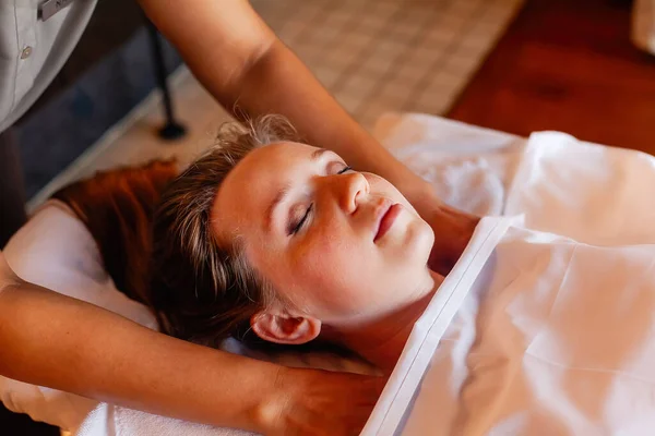 Woman gets body massage in spa salon. Healthy lifestyle and body care concept. Female person with closed eyes on massage table gets therapy in luxury spa salon. Masseur make medical massage for client