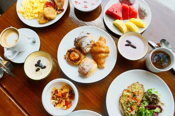 Buffet hotel breakfast served with fresh croissants, fruits, omelette, muesli, avocado toast, tea and coffee cup. Table with variety of morning food in luxury resort. Balanced diet
