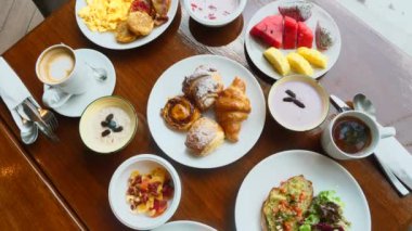 Buffet hotel breakfast served with fresh croissants, fruits, omelette, muesli, avocado toast, tea and coffee cup. Table with variety of morning food in luxury resort. Balanced diet