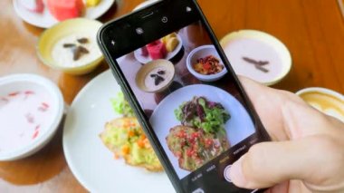 Man hand take photos of breakfast by mobile phone. Healthy food with avocado toast and muesli