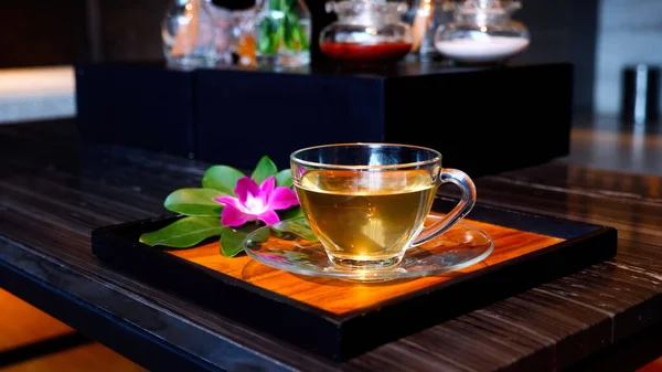 A cup of herbal ginger tea after relax massage at resort and spa salon. Healthy drinking water on tray with orchid flower in spa salon