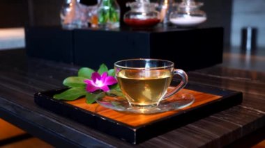 A cup of herbal ginger tea after relax massage at resort and spa salon. Healthy drinking water on tray with orchid flower in spa salon