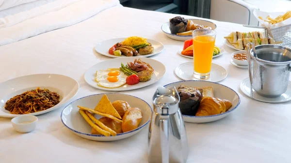 Breakfast in bed, cozy hotel room. Concept of holidays, vacation in luxury resort. Order of fresh food in hotel restaurant, room service. Delicious food with eggs, bacon, pasta and orange juice on bed