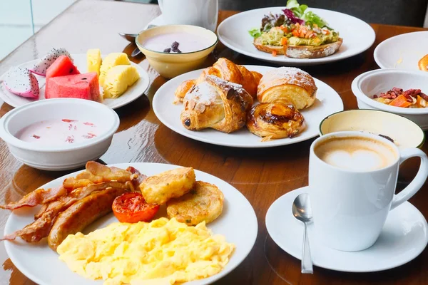 早餐在茶几上 盛满了新鲜食物 有鳄梨吐司 羊角面包 热带水果和一杯咖啡 现代酒店的自助早餐早餐 — 图库照片