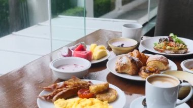 Kafede kahvaltı. Avokado tostlu taze yemek, kruvasan, yumurta, tropikal meyve ve bir fincan kahve. Modern otelde açık büfe sabah yemeği.