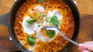 Kadın eli demir tavadan Shakshouka ya da Shakshuka alır. Domates soslu yumurta, soğan ve maydanozlu Orta Doğu yemeği. Keto yemeği, az karbonhidrat. Üst görünüm