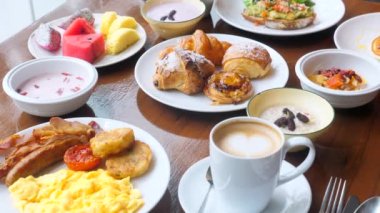 Otelde büfe mutfak kahvaltı masası. Lüks restoranda omlet, taze meyve, kruvasan ve kapuçino ile dolu ahşap masa..