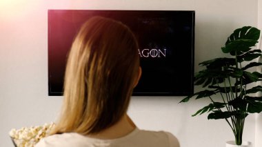 Tanımlanamayan bir kadın evde dinleniyor ve TV 'de Dragon HBO TV dizisini izliyor ve patlamış mısır yiyor. Game of Thrones 'un ön bölümü. Phuket, Tayland - Eylül, 2022