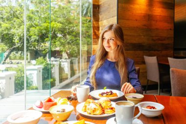 Attractive woman on breakfast in hotel restaurant. Businesswoman on meeting dine in modern cafe, drinking coffee. Business lunch concept