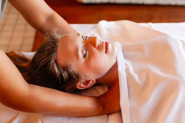 Woman gets body massage in spa salon. Healthy lifestyle and body care concept. Female person with closed eyes on massage table gets therapy in luxury spa salon. Masseur make medical massage for client