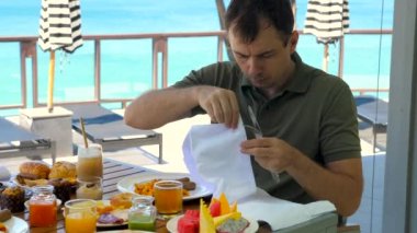 İlk kez kafası karışmış bir adam yurt dışında, Tayland 'da, egzotik bir otelde tatil yapıyor. Açık büfede erkek turist kahvaltısı ya da kafeteryada brunch, kumaş peçeteden çatal bıçak takımı alarak, yemek yemeye hazır olun..