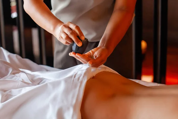 Woman gets body massage in spa salon. Healthy lifestyle and body care concept. Female person on massage table gets therapy in luxury spa salon. Masseur make medical massage for client