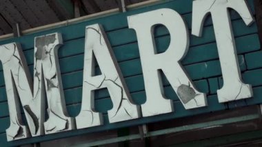 Boş süpermarketteki eski çatlak tabelası, harfleri soyulmuş. Terk edilmiş şehirde klasik market tabelası. Korku ya da Cadılar Bayramı dekorasyonu kavramı