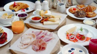 Lüks restoranda kahvaltı ya da öğle yemeği. Masa lezzetli yiyeceklerle dolu. Peynir, somon, jambon, fırın ve meyve suyu. Otelde açık büfe yemeği. Çeşitli atıştırmalıklar ve aperatiflerle sabah yemeği..