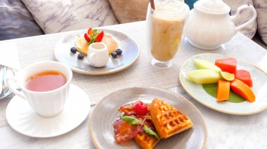 Açık kafede çay ve kahve eşliğinde tatlı yiyecekler. Pankek ve Belçika waffle 'ıyla otelde kahvaltı. Tatil köyünde sabah yemeği, hamur işleri, meyve, buzlu kapuçino ve çaydanlık. Otel tatili