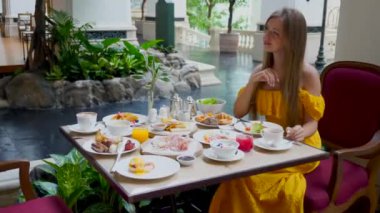 Genç bir kadın lüks otel restoranında akşam yemeğinde ya da öğle yemeğinde taze meyve suyu içer. Çekici bir kadın kahvaltı yapar, lüks bir restoranda oturur. Açık büfe sabah yemeği..