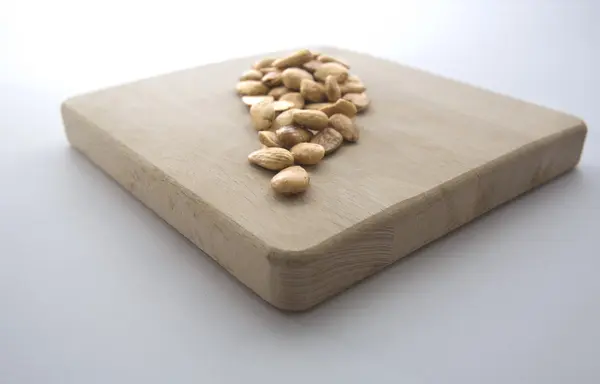 Fried almonds over wooden board — Stock Photo, Image