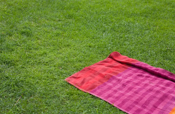 Red towell over the green grass — Stock Photo, Image