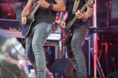 Hard rock müzisyenleri sahne alıyor. Gitarist ve bas gitar.