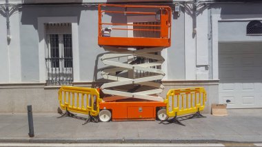 Elektrikli mobil hava çalışma platformu. Profesyonel ressamlar kaldırıma park etmiş makas kaldıracı.