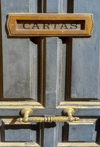 Built-in letter box on dusty old wooden door. Spanish caption, Selective focus