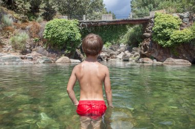 Child boy at La Maquina Natural swimming pool. Crystal-clear waters spot in the heart of La Vera County, Caceres, Extremadura, Spain