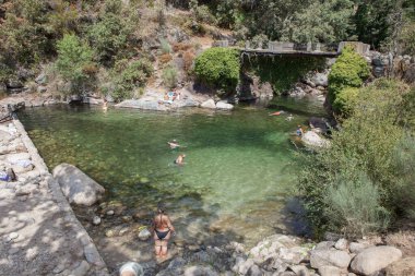 Guijo de Sta Barbara - August 25th, 2022: Visitor enjoying La Maquina Natural swimming pool, Guijo de Santa Barbara, Spain. Crystal-clear waters spot in the heart of La Vera County, Caceres, Extremadura
