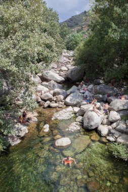 Guijo de Sta Barbara - August 25th, 2022: Visitors enjoying La Maquina Natural swimming pool, Guijo de Santa Barbara, Spain. Crystal-clear waters spot in the heart of La Vera County, Caceres, Extremadura