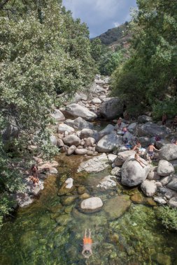 Guijo de Sta Barbara - August 25th, 2022: Visitors enjoying La Maquina Natural swimming pool, Guijo de Santa Barbara, Spain. Crystal-clear waters spot in the heart of La Vera County, Caceres, Extremadura