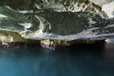 Deniz suyuyla dolu bir kayanın içinde belirgin taş dokusu olan bir mağara.