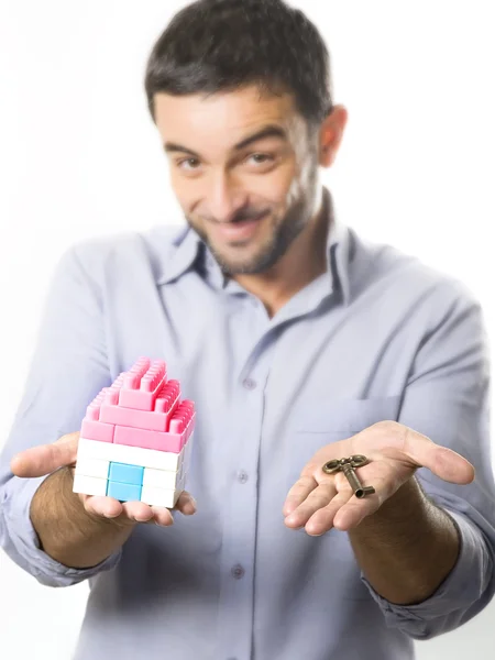 Junger Mann präsentiert Miniaturhaus und Schlüssel — Stockfoto