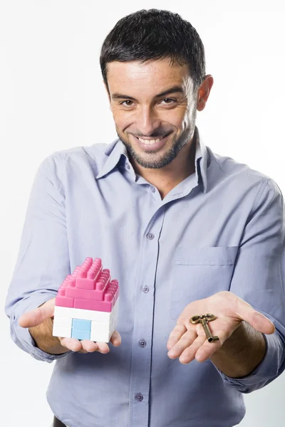 Young Man presenting Miniature House and Key — Stock Photo, Image