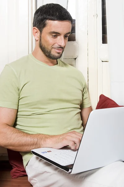 Jovem feliz trabalhando no laptop em casa — Fotografia de Stock