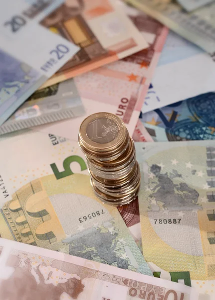 Евро банкноты и стопка монет изолированы — стоковое фото