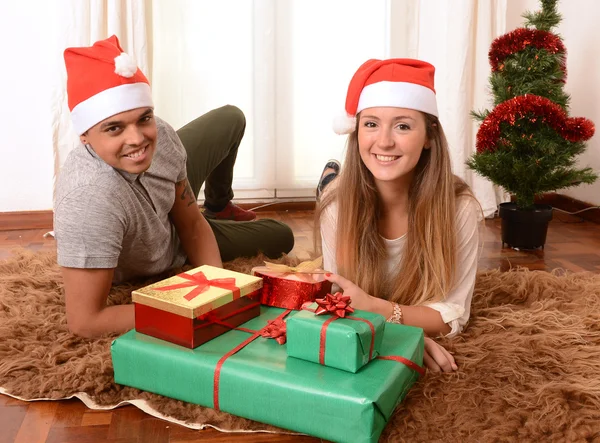 Joven pareja feliz en la alfombra en Navidad con regalos —  Fotos de Stock