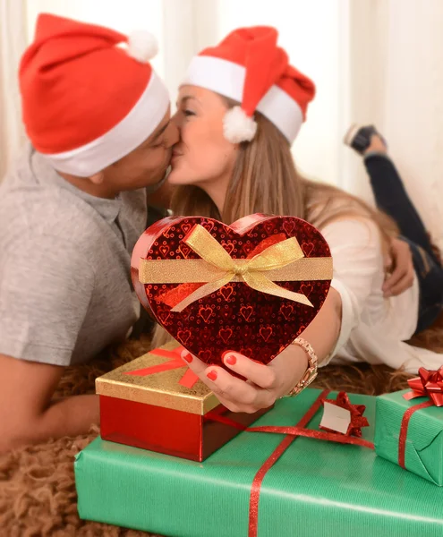 Young Happy Couple Kissing on rug at Christmas Royalty Free Stock Images