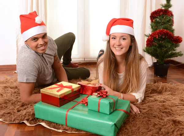 Młoda szczęśliwa para na dywan na Boże Narodzenie prezenty Zdjęcie Stockowe