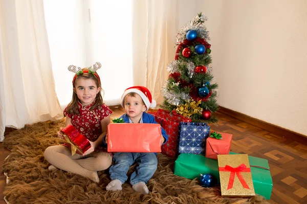 Mutlu sevimli küçük çocuk Noel Baba şapkası ve güzel kız kardeşi — Stok fotoğraf