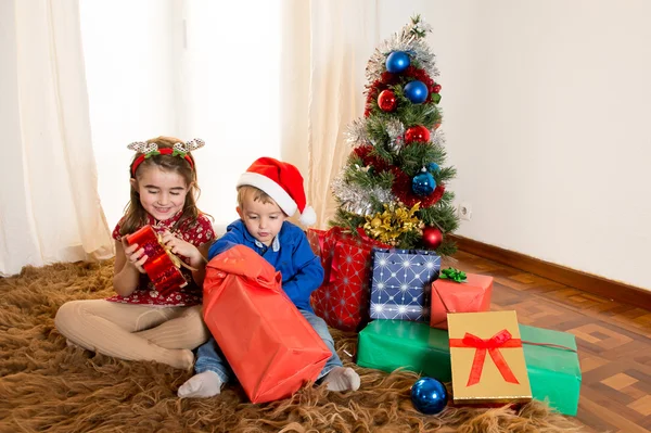 Małe dzieci na dywan otwarcie Boże Narodzenie prezenty — Zdjęcie stockowe