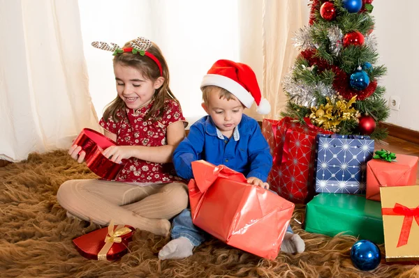 Little kids on rug opening Christmas Presents — Stock Photo, Image