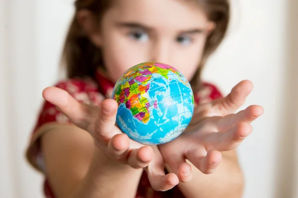 Linda chica sosteniendo el pequeño globo del mundo en sus manos — Foto de Stock